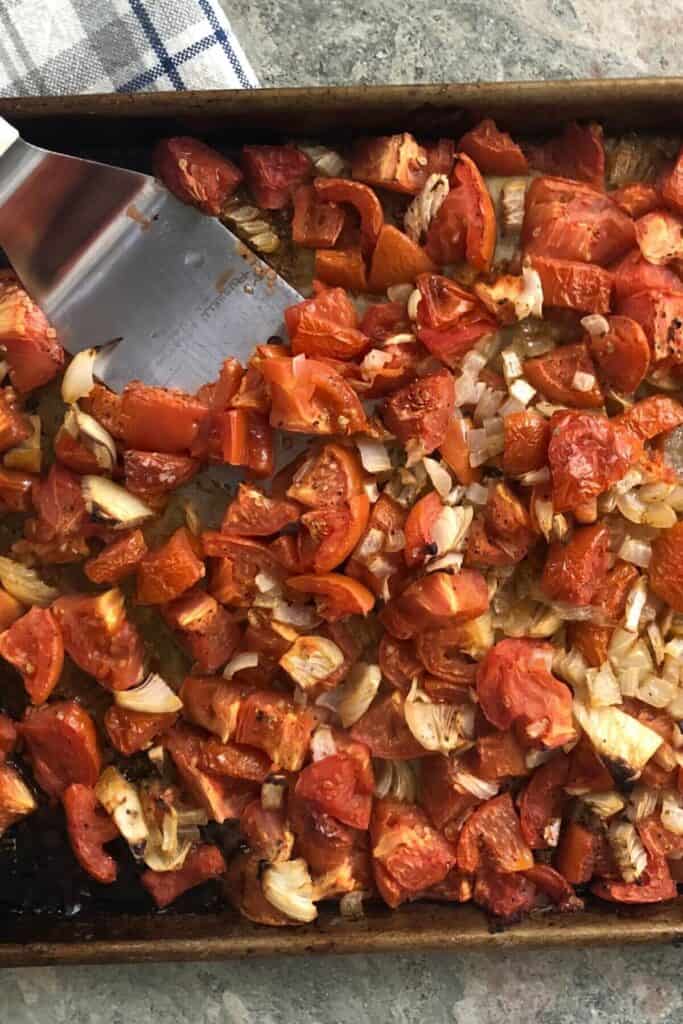 Roasted tomatoes, onions and garlic on a pan.