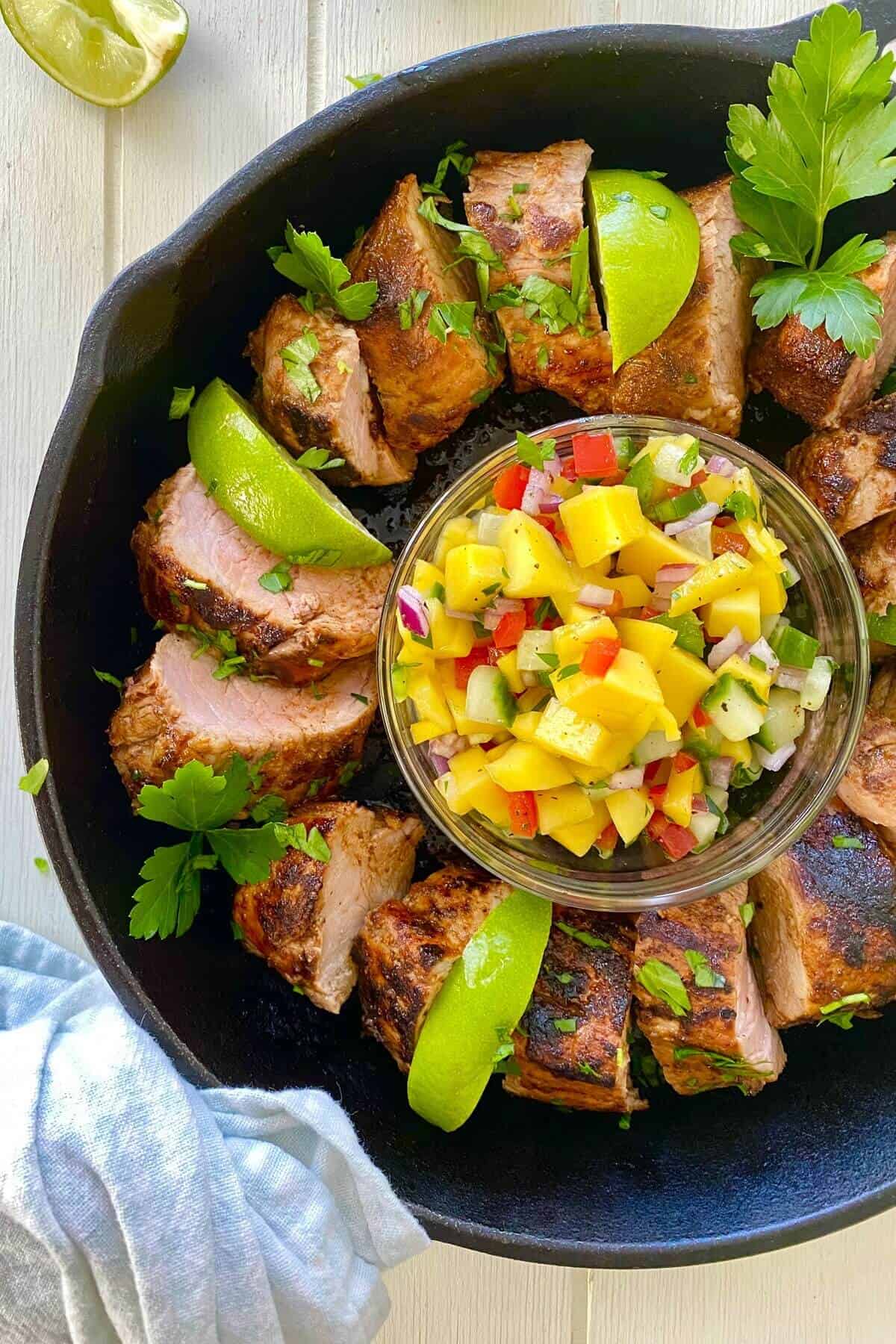 sliced pork with mango in a cast iron skillet.