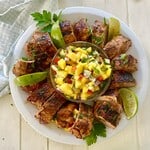 A sliced pork tenderloin on a plate with a mango salsa.