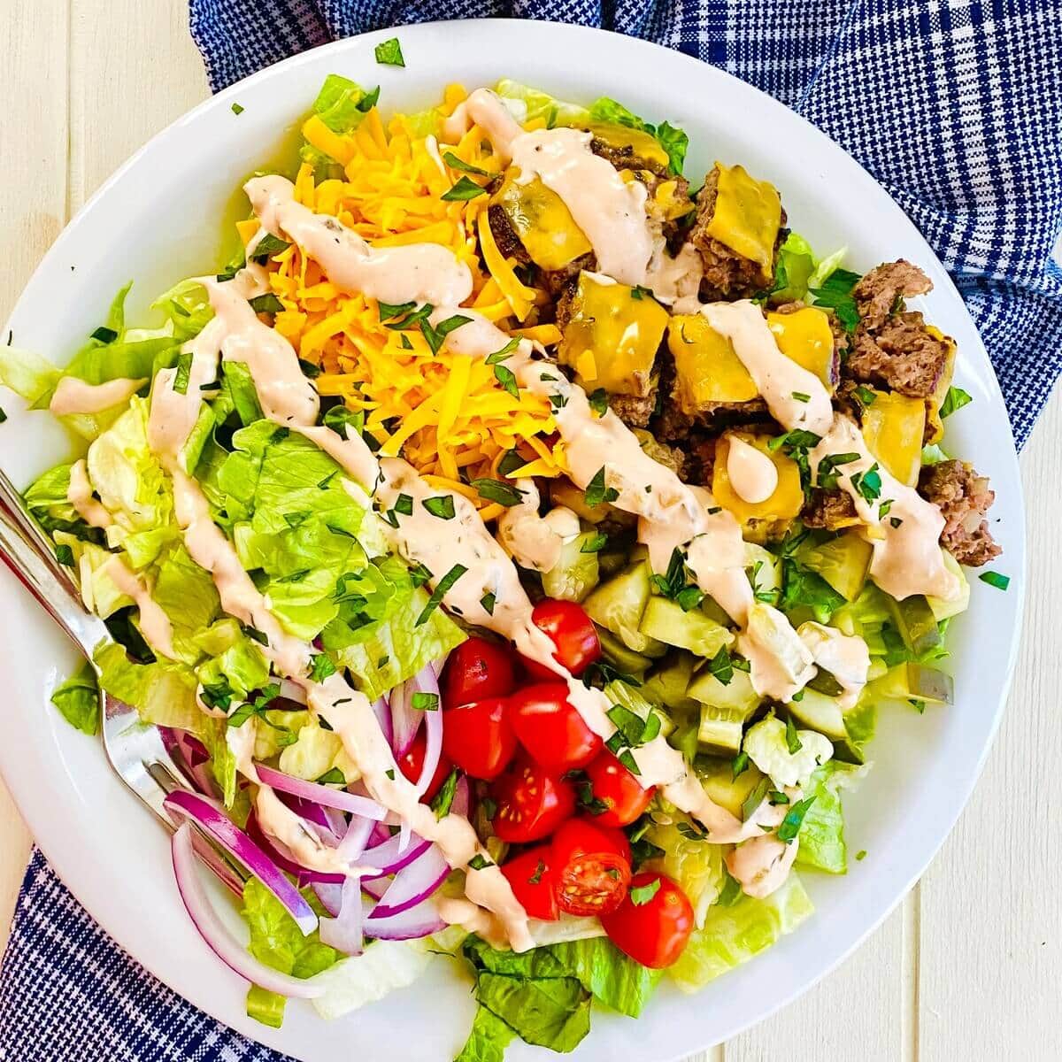 A Big Mac Bowl cheeseburger salad with a blue napkin.