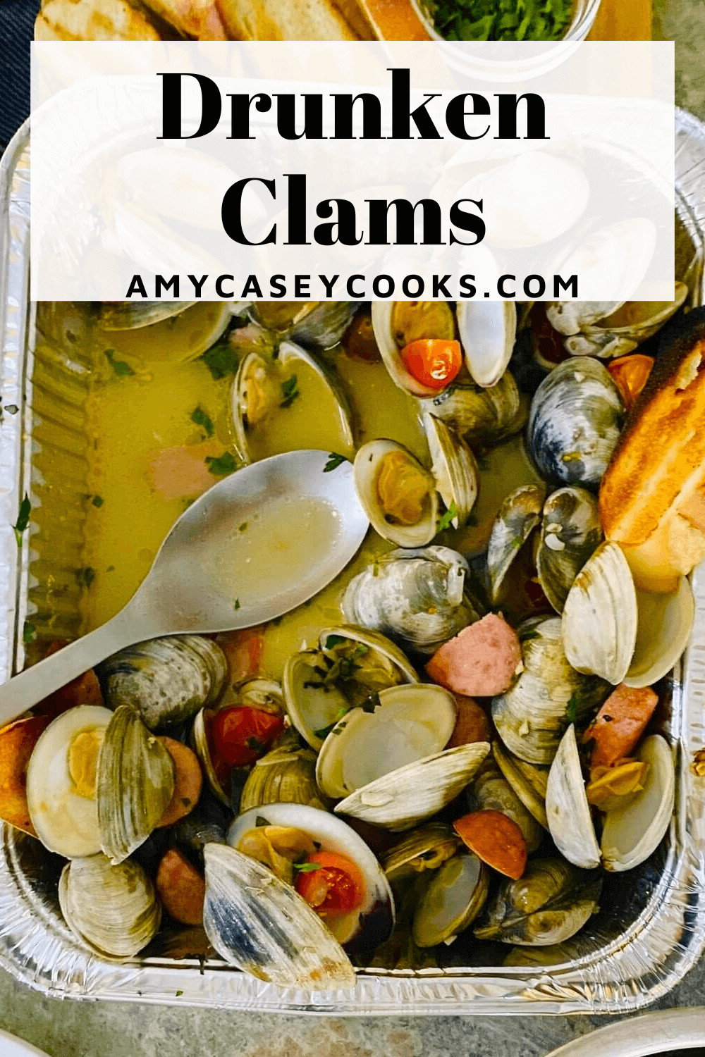 clams and sausage in a foil pan with a spoon.