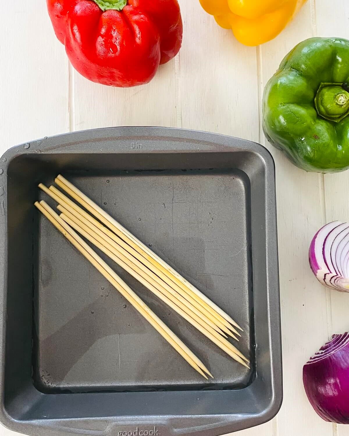 A pan of water with wooden skewers in it.