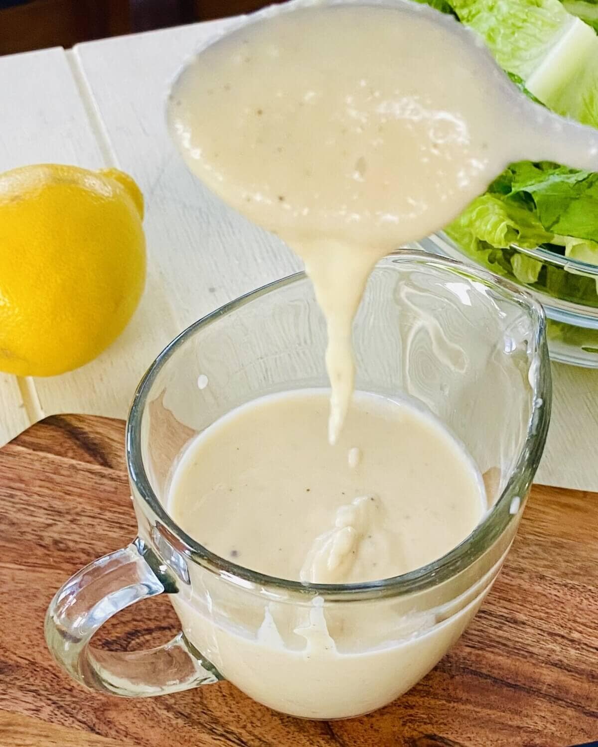 Caesar dressing drizzling off a spoon.