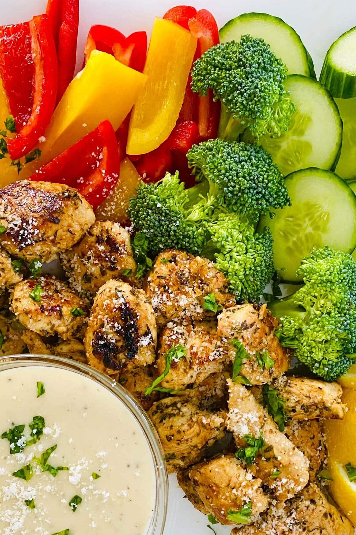 plated Italian herb chicken, vegetables and dip.