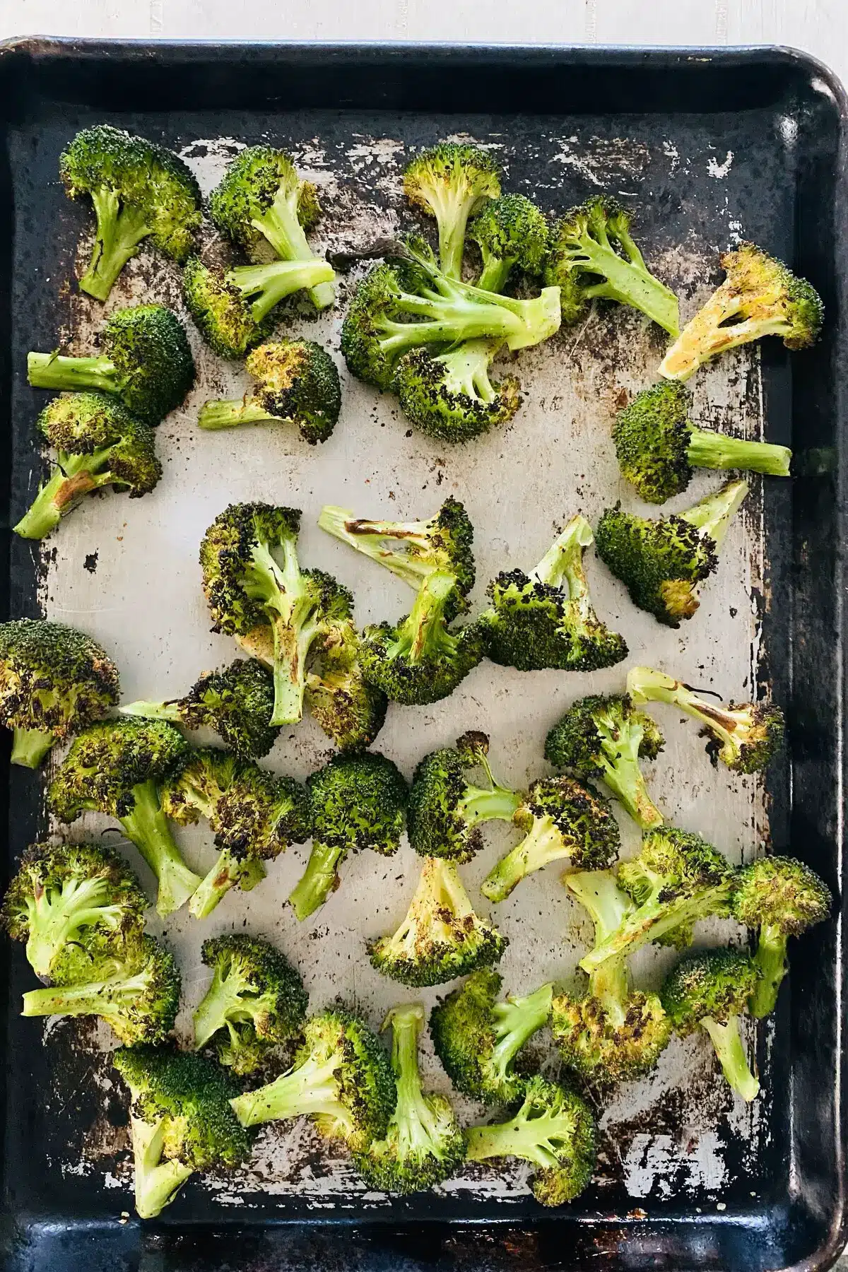 broiled broccoli recipe with broccoli on a sheet pan.