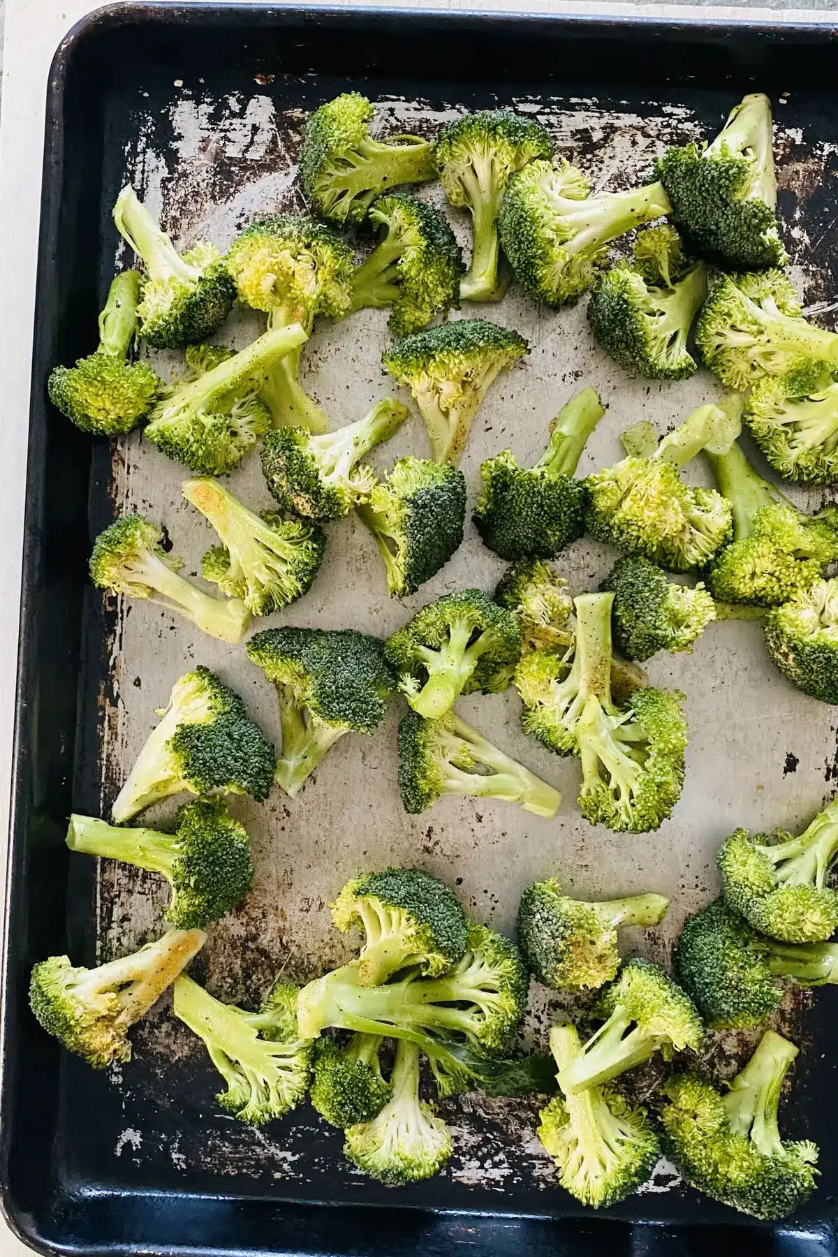 raw broccoli seasoned and on a baking sheet.