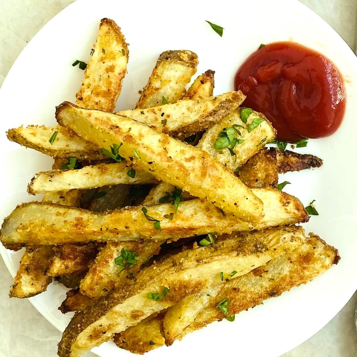 A plate of oven baked french fires with ketchup.