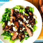 A serving of steak salad with roasted onions and blue cheese.