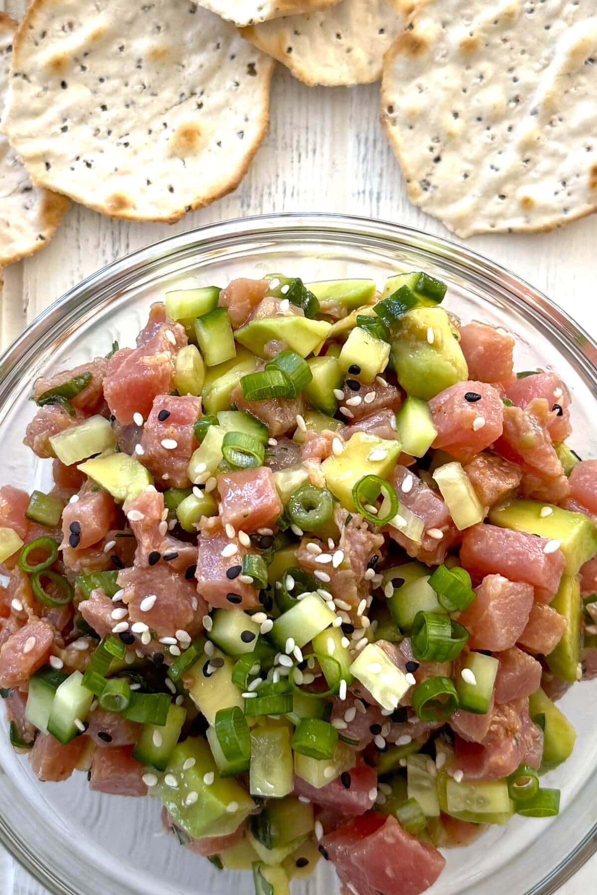 A bowl of tuna ceviche with water crackers.