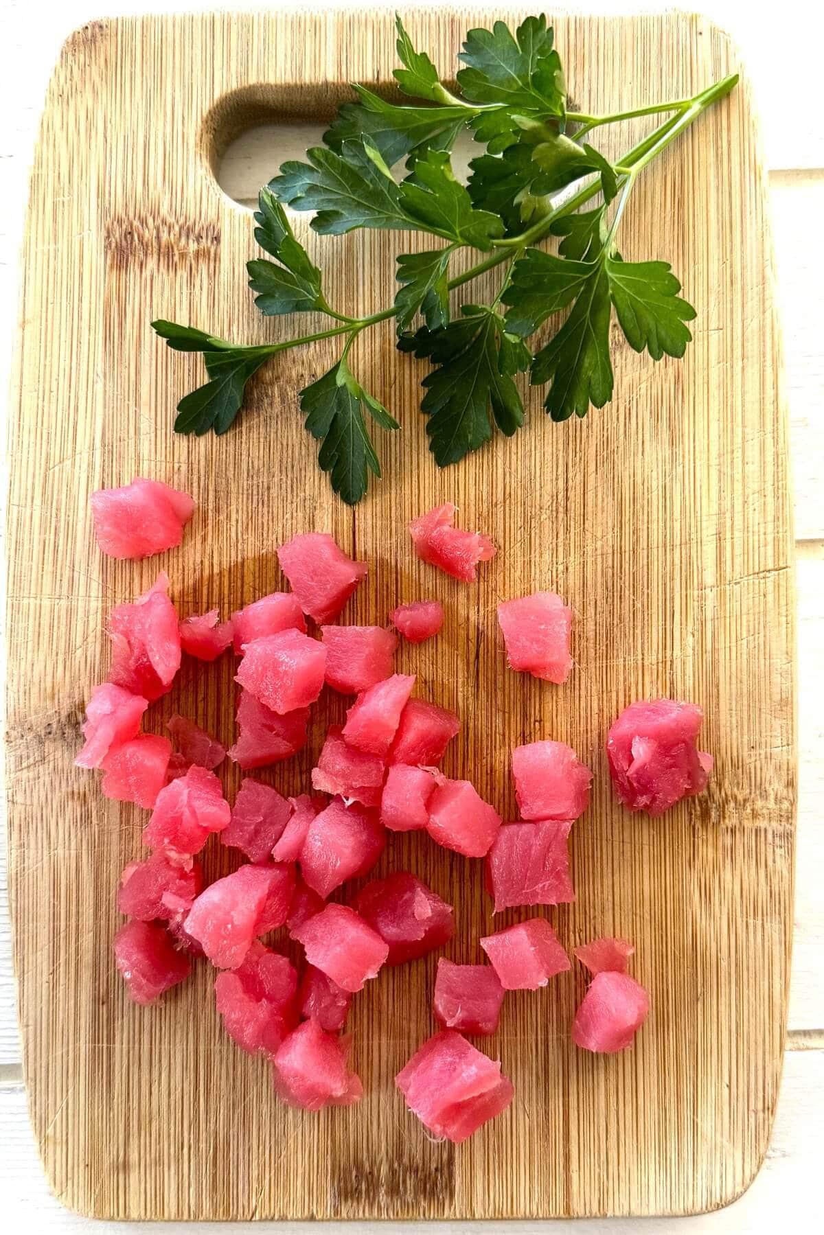 Cubes of raw tuna on a cutting board.