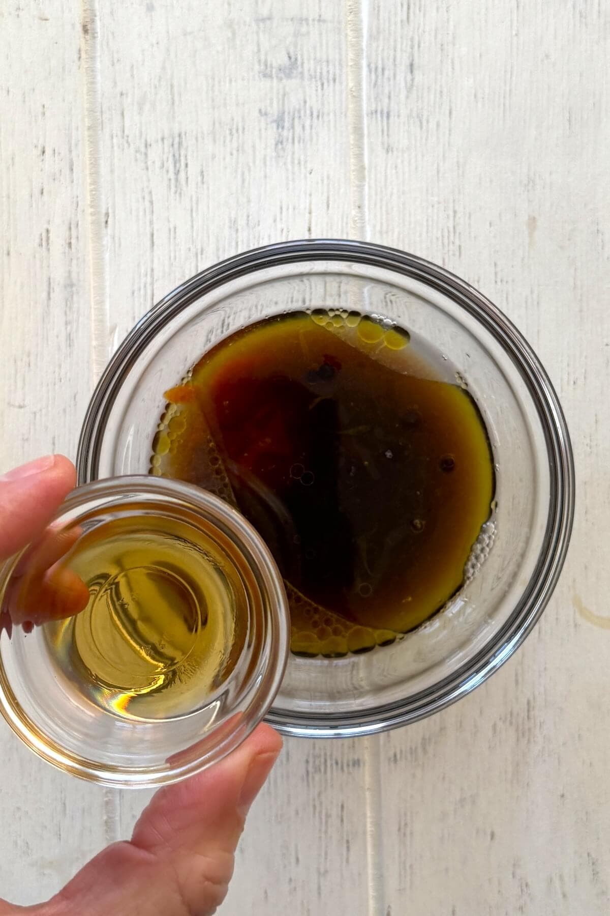 Adding toasted sesame oil in a bowl.