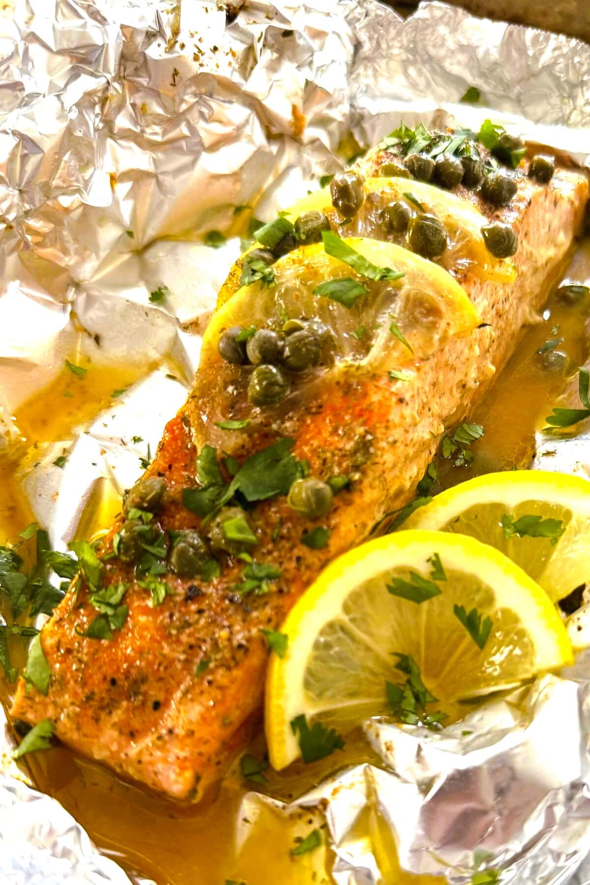 Salmon in foil in oven with lemons.