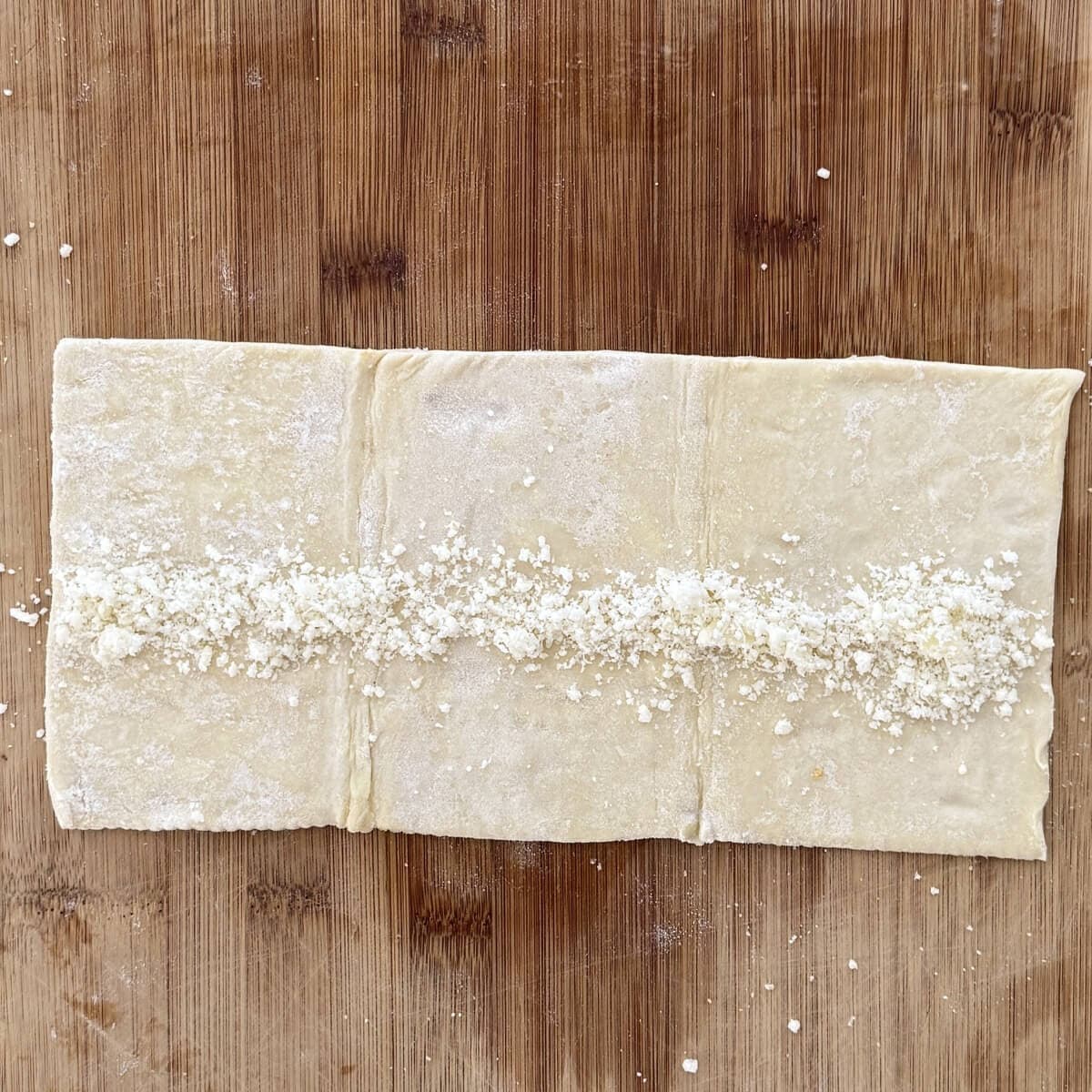 A sheet of puff pastry with cheese on it.
