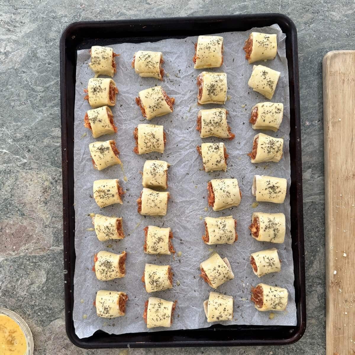 Unbaked homemade sausage rolls on a sheet pan.