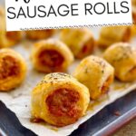 Sausage rolls on a parchment paper lined baking sheet.