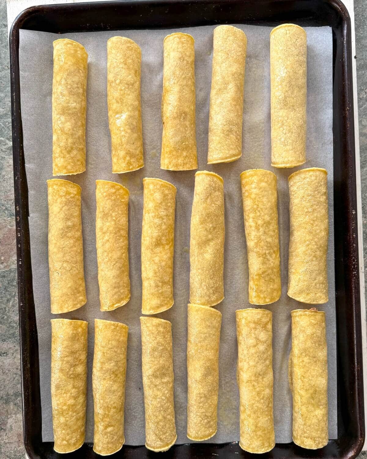 Taquitos on a baking sheet.