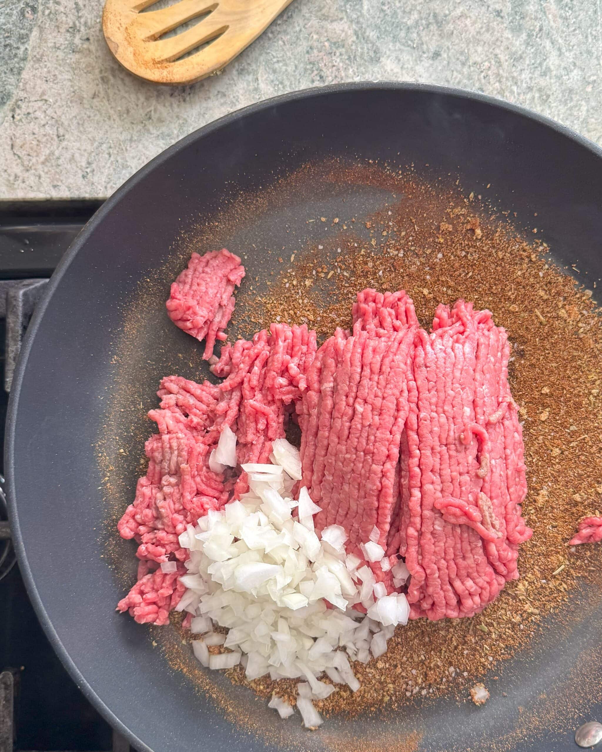 Ground beef, diced onion and spices in a sauté pan.