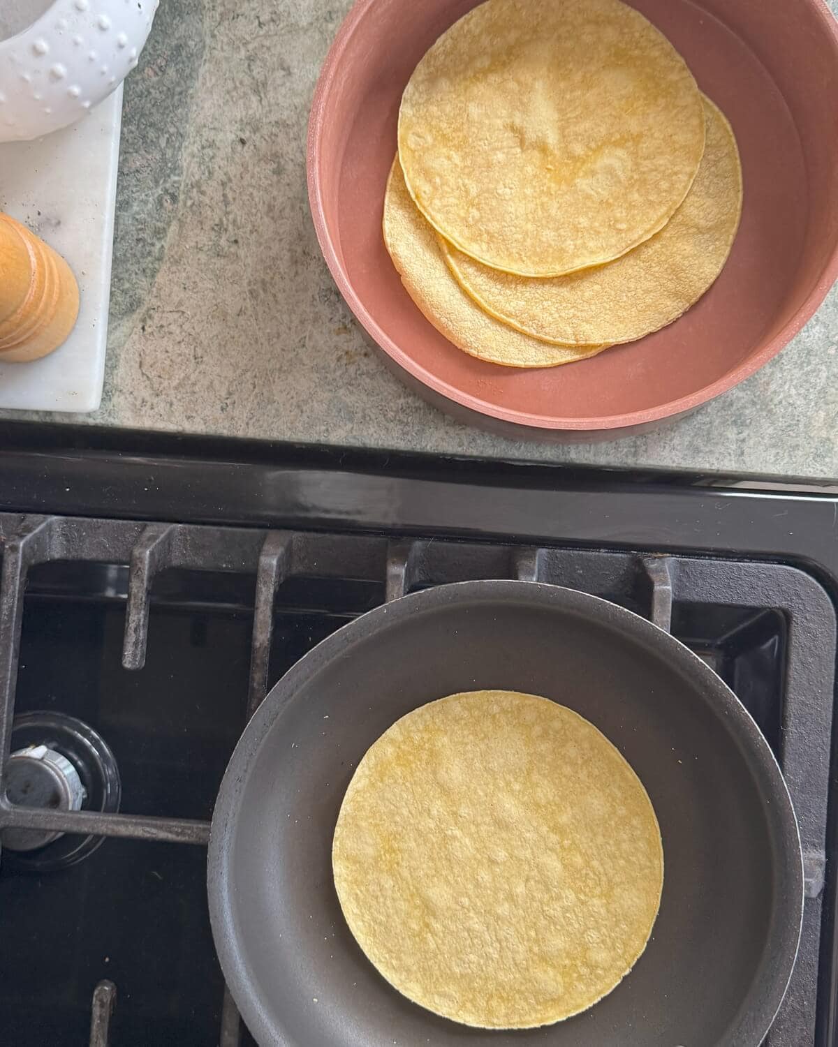 Warming corn tortillas in a pan and a tortilla warmer.