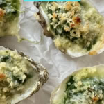 Baked Rockefeller oysters on a white plate.