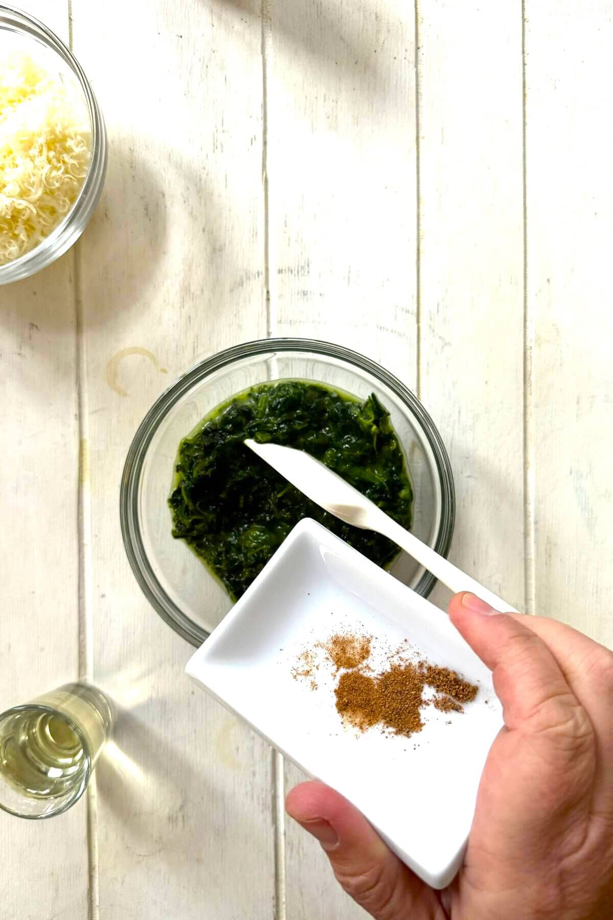 Combining creamed spinach, wine, and nutmeg for Rockefeller oysters.