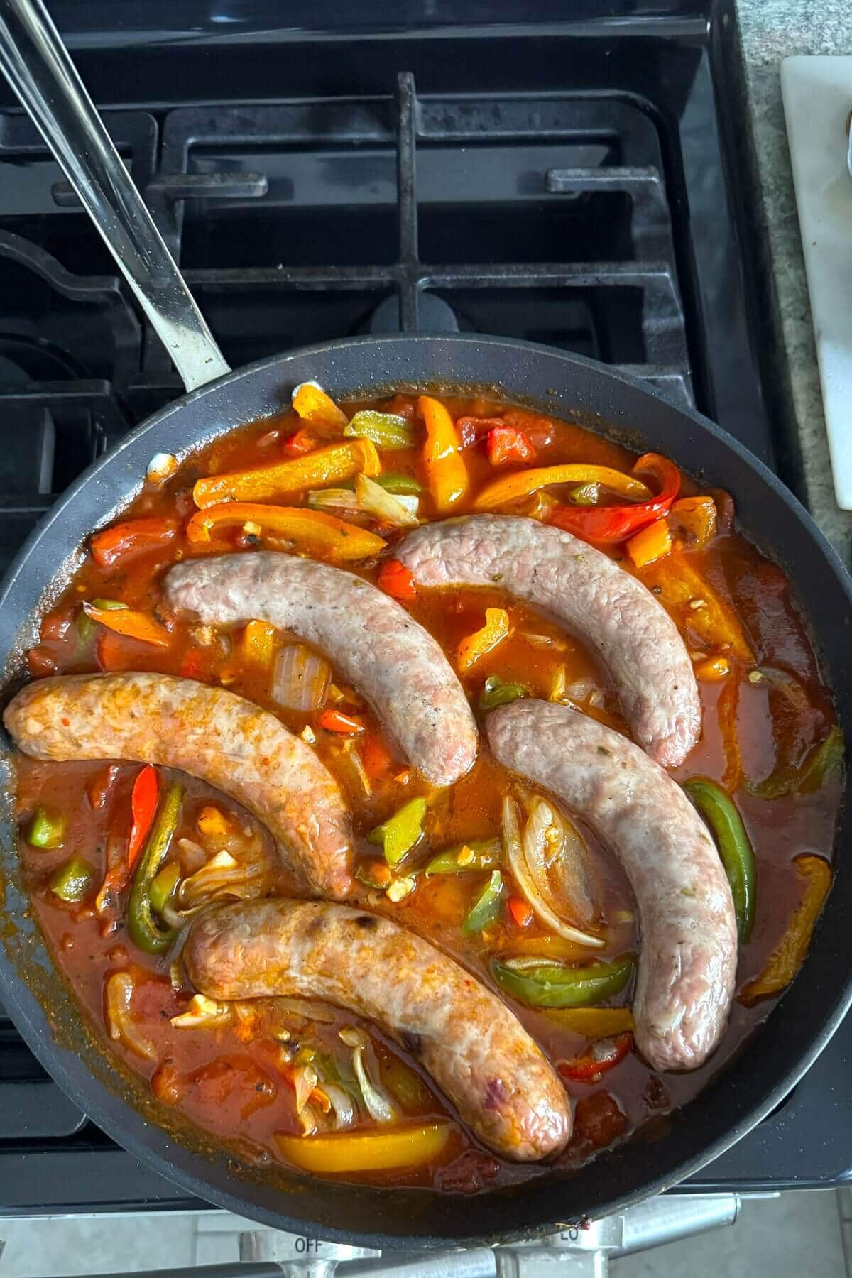 Cooked Italian sausage and peppers in a skillet.